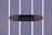 A close-up view of a decorative black mail slot on a gray paneled door. The door features vertical white stripes that contrast with the dark metal of the mail slot, which has intricate designs on its ends.