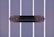 A close-up view of a decorative black mail slot on a gray paneled door. The door features vertical white stripes that contrast with the dark metal of the mail slot, which has intricate designs on its ends.