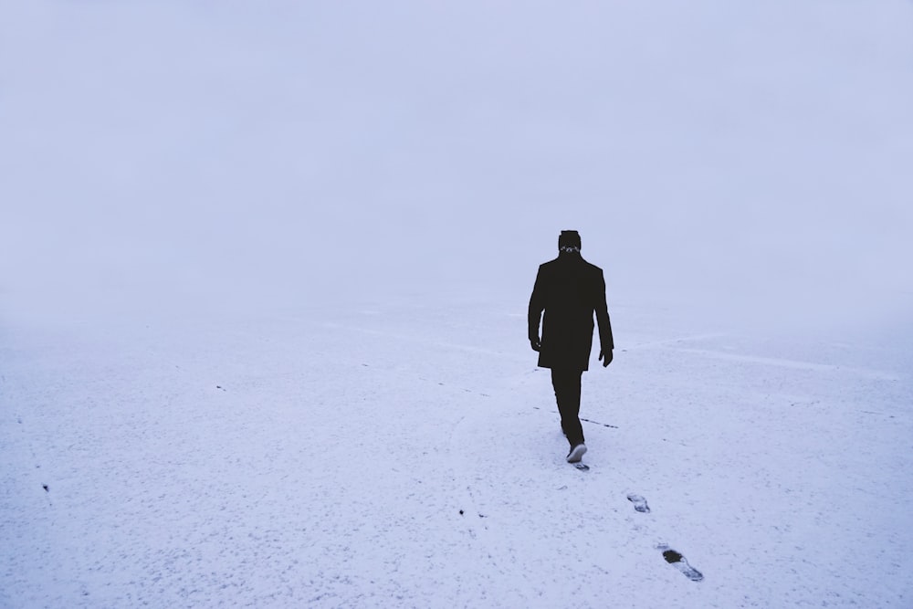 a man walking across a snow covered field