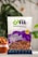 A clear plastic bag containing California almonds is prominently displayed against a blurred background with greenery. The packaging includes branding with the logo '82fit feeding india by zomato' and a purple design with health benefits and 'premium quality' label. A bowl filled with almonds is partially visible on the left.