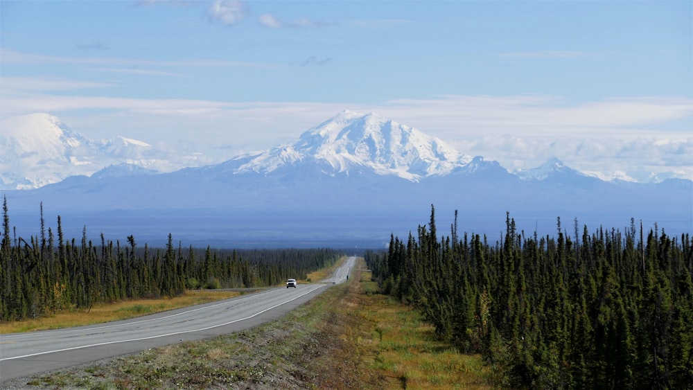 a car driving down a road with a mountain in the background