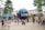 A large globe structure with the letters 'UNIVE' visible, surrounded by a crowd of people taking photos and walking around. The area is lush with palm trees and modern architectural elements, possibly in an amusement or theme park setting.