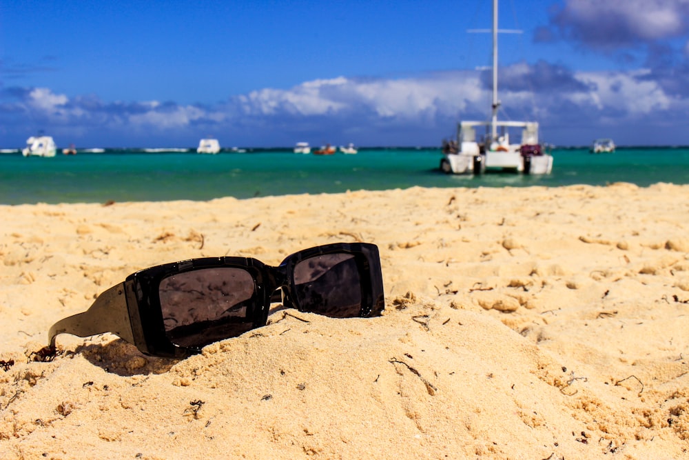 a pair of sunglasses sitting on top of a sandy beach