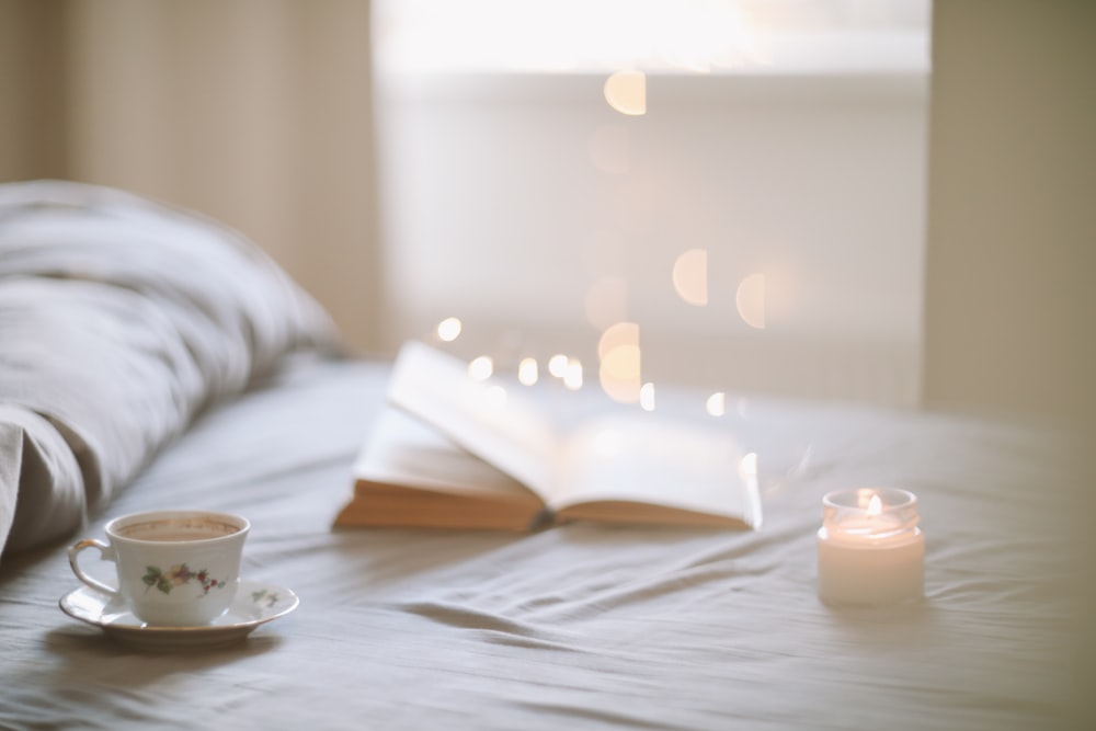 a cup of coffee and a book on a bed