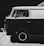 A classic van is parked against a dark background. The van has a two-tone paint job with a light upper part and a darker lower part. The image is in black and white, highlighting the contrast and texture. Various stickers are visible on the window, adding a personalized touch. The clean, reflective surface of the vehicle and the old-fashioned style give it a retro feel.