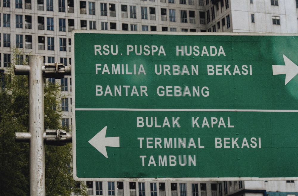 a green street sign in front of a tall building