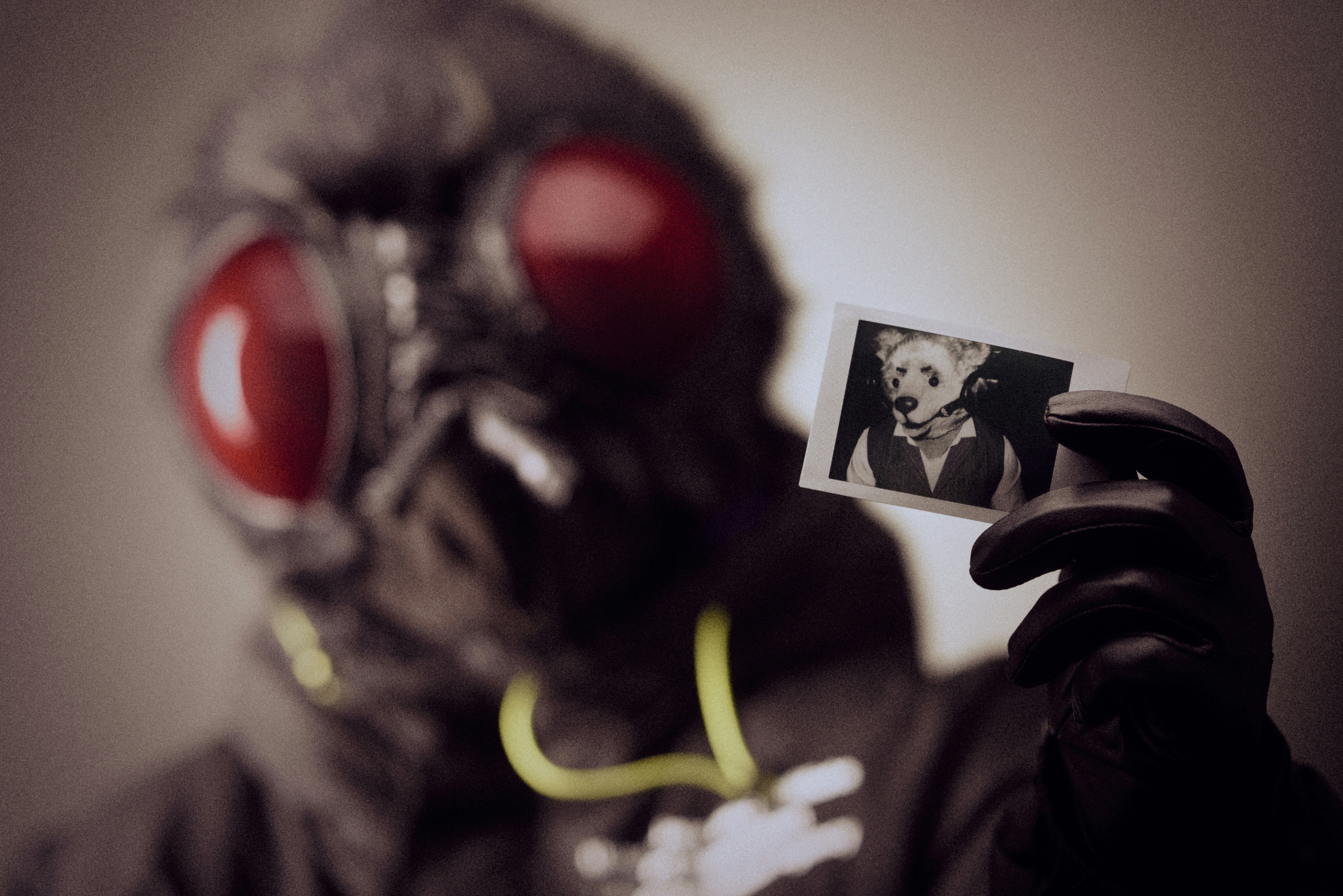 A man in a gas mask holding up a card with a picture of a woman