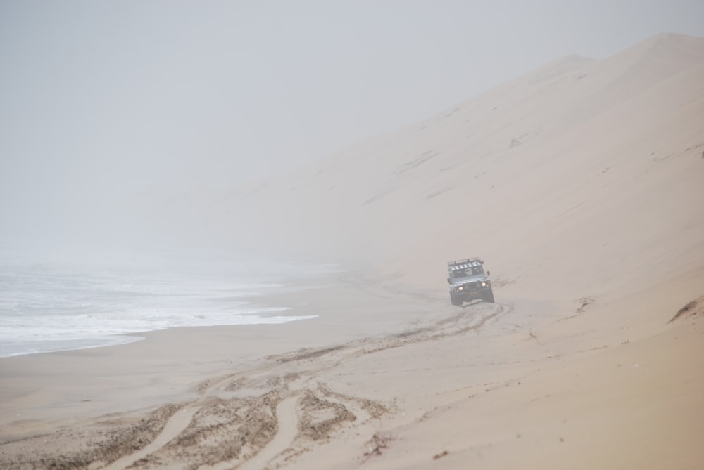 um caminhão dirigindo por uma praia de areia ao lado do oceano
