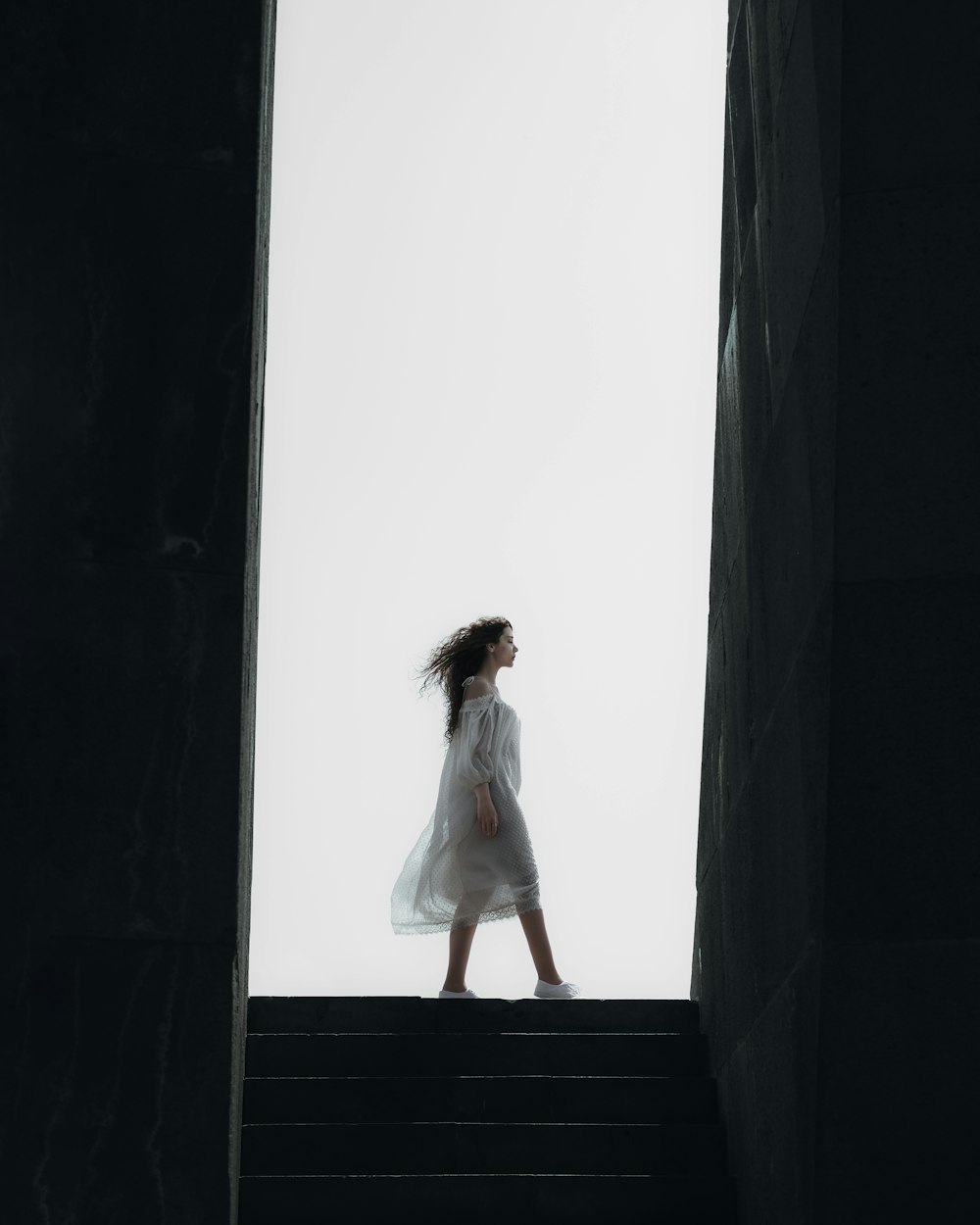 a woman in a white dress walking up some stairs