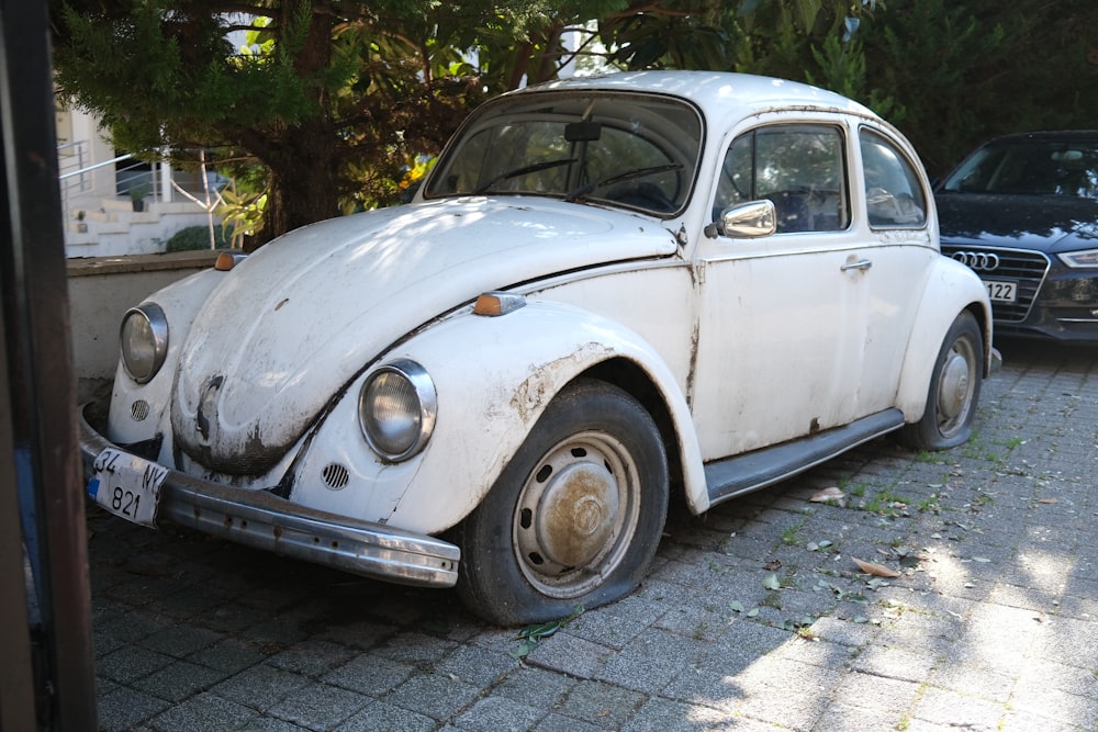 Ein alter weißer Käfer parkt am Straßenrand