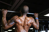 Athlete mid-pull-up with black background and red lighting.