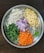 A round metal tray features neatly chopped vegetables, including cauliflower, potatoes, green beans, red onions, carrots, and green chili peppers. Each type of vegetable is organized into a distinct section, showcasing a variety of colors and textures.