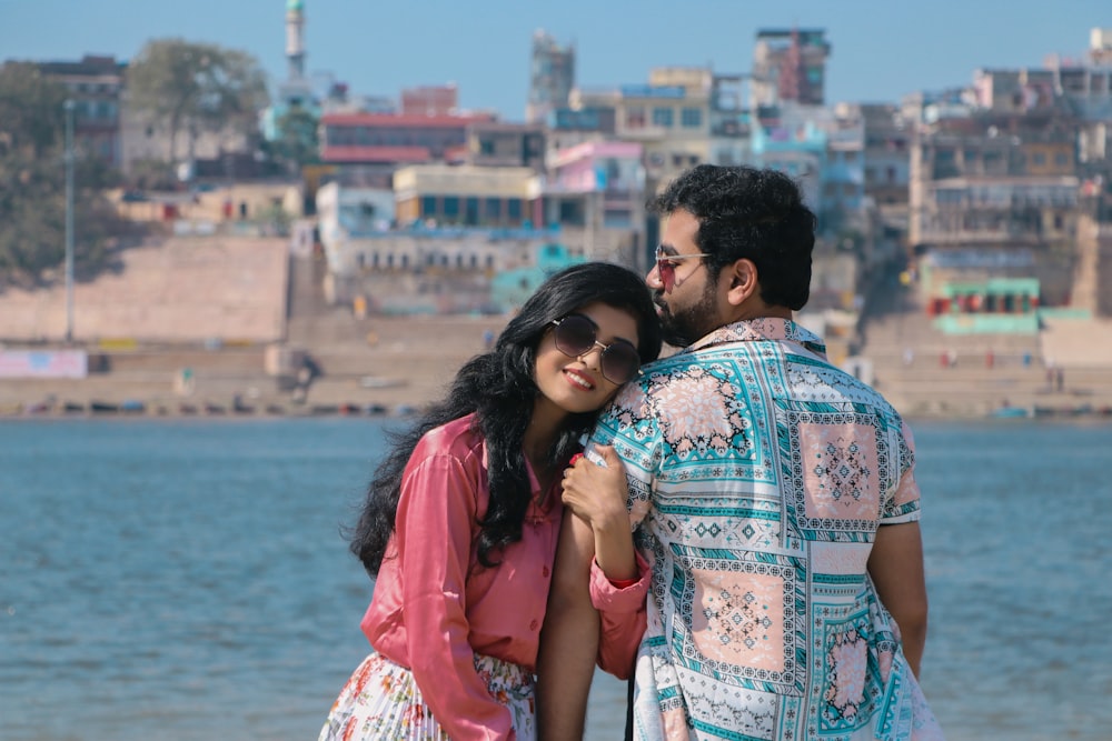 a man and woman standing next to each other near a body of water