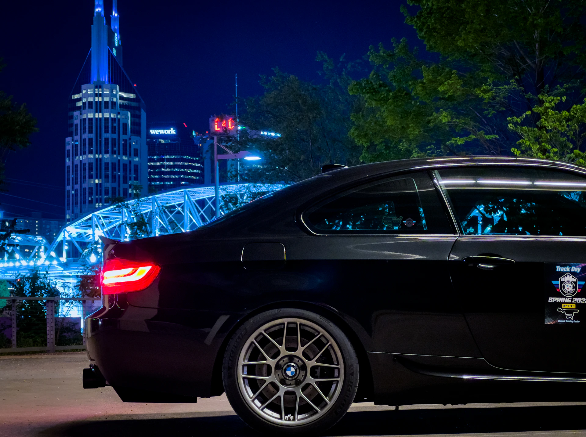 A sleek black Cadillac Escalade parked in front of a modern city skyline at dusk, illuminated by golden streetlights.