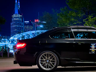 Sleek black luxury cab parked against a city skyline at dusk, highlighted with golden accents.