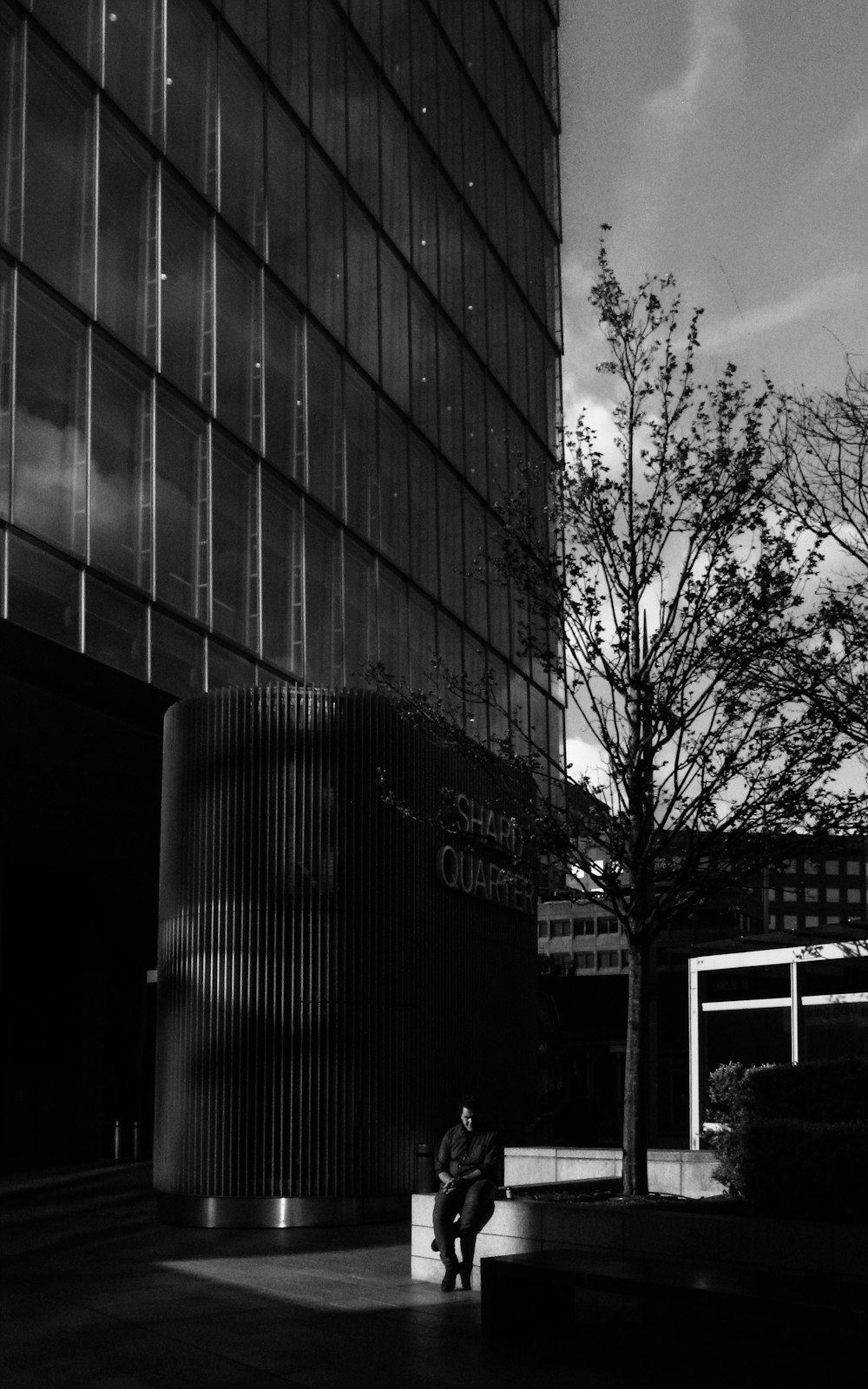 a person sitting on a bench in front of a tall building