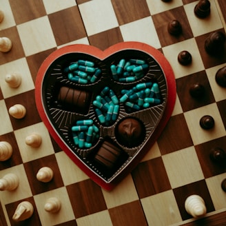 a heart shaped box of chocolates on a chess board