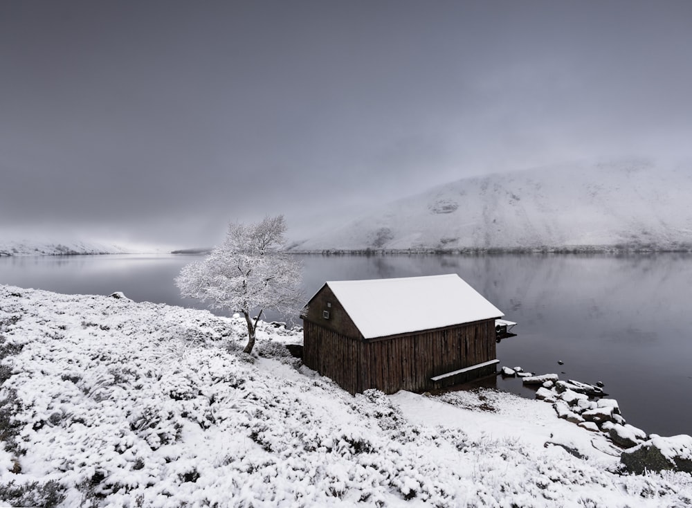 雪に覆われた湖のほとりにある小さな小屋