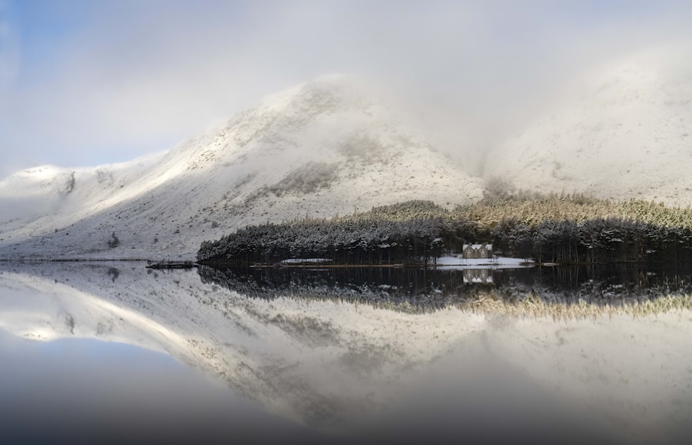 a snow covered mountain with a lake in the foreground