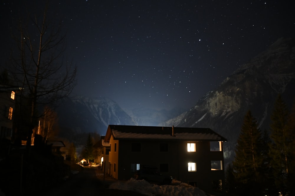 a house is lit up at night in the mountains