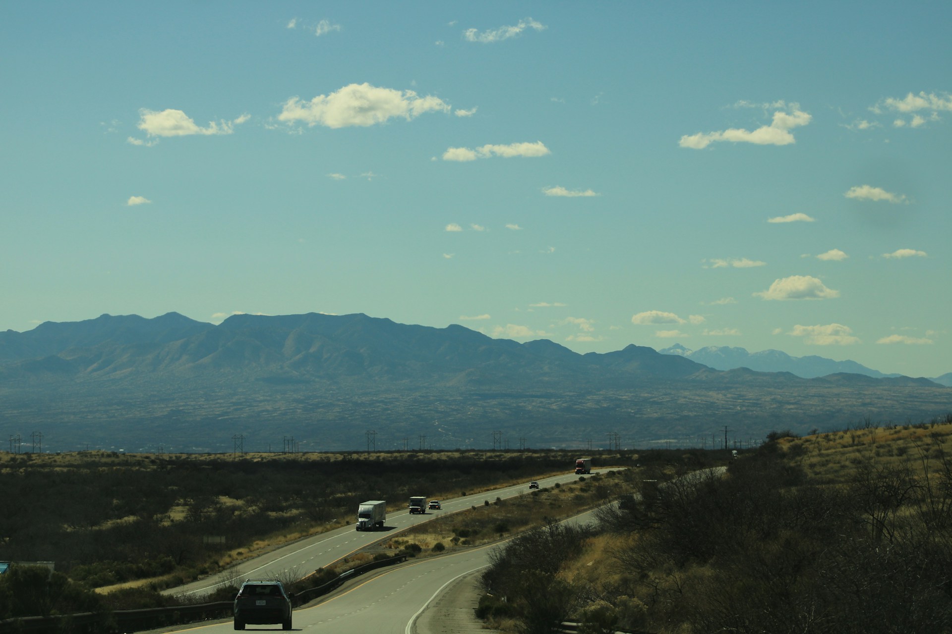 Scenic desert road with majestic mountains as a Rehal Ride van approaches Medina, capturing the peaceful journey of pilgrims.