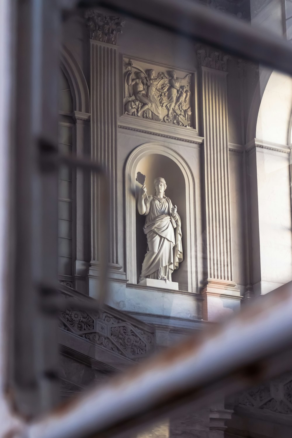 a statue of a man holding a book in front of a window