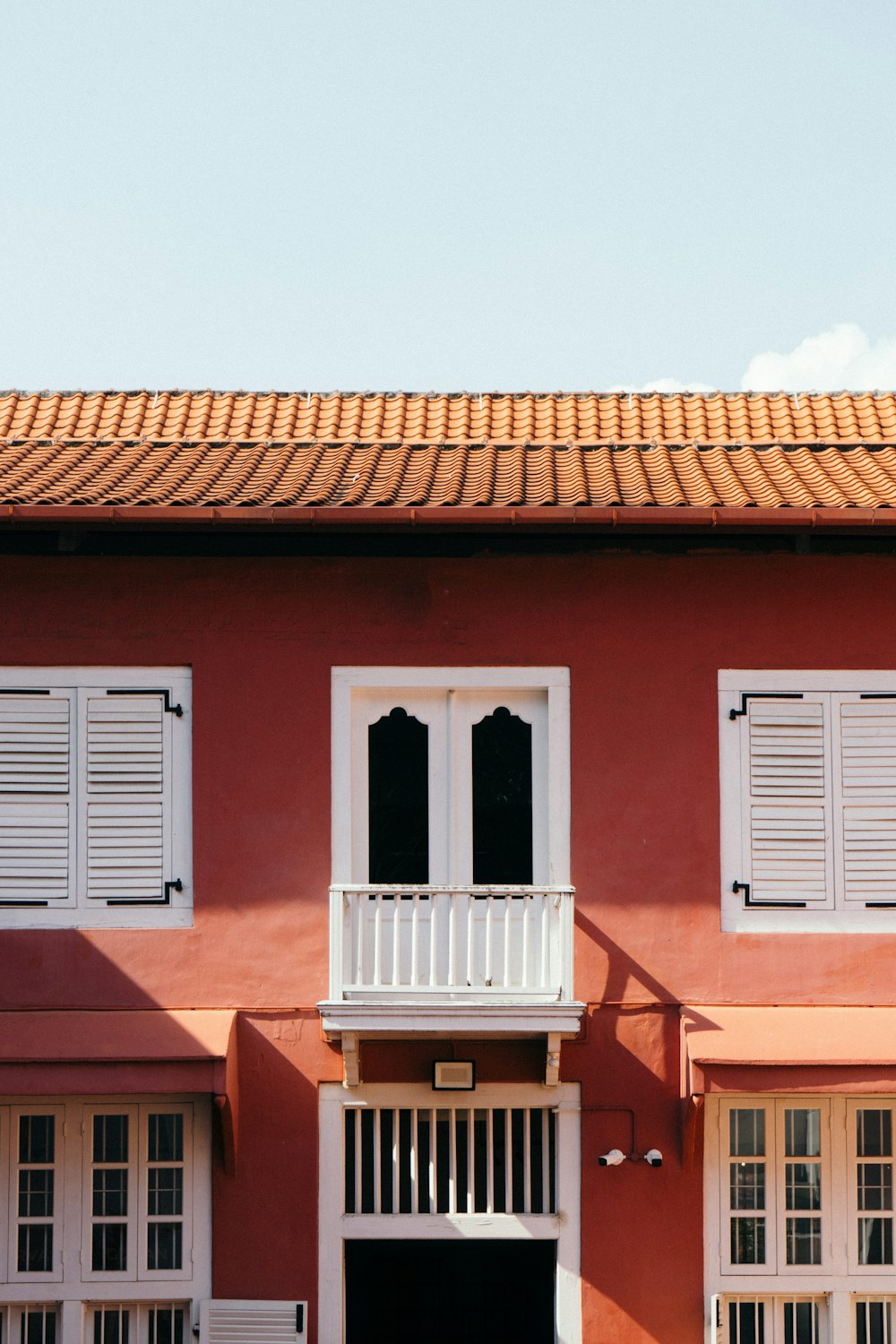 a red building with white shutters and a balcony