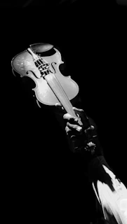 Artistic image of a vintage violin with warm lighting emphasizing its curves, floating subtly against a black backdrop.