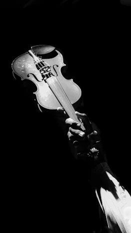 Artistic image of a vintage violin with warm lighting emphasizing its curves, floating subtly against a black backdrop.
