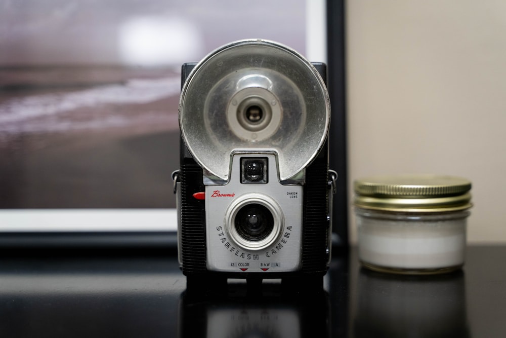a camera sitting on top of a table next to a jar