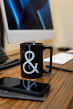 a black coffee mug sitting on top of a wooden desk