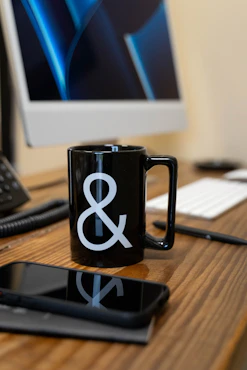 a black coffee mug sitting on top of a wooden desk