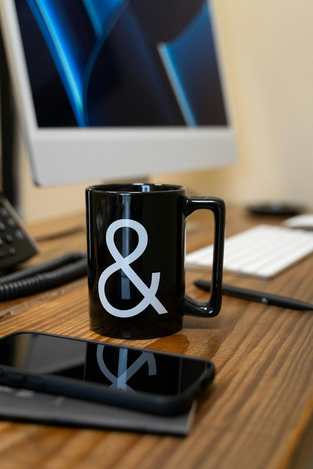 a black coffee mug sitting on top of a wooden desk