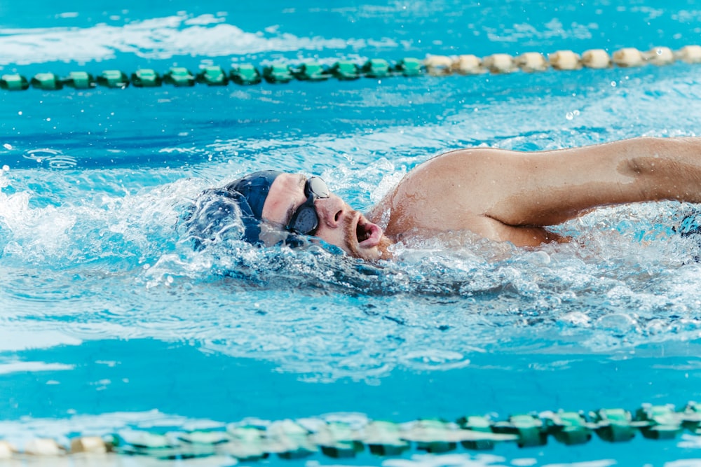 Foto Um homem nadando em uma piscina vestindo uma touca de natação – Imagem  de Pessoa grátis no Unsplash