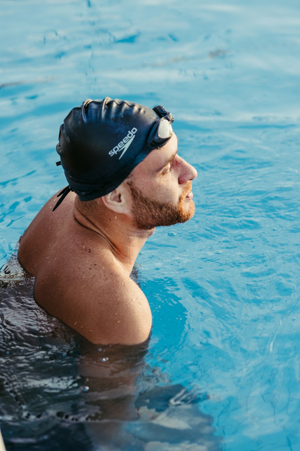 a man swimming in a pool wearing a swimming cap