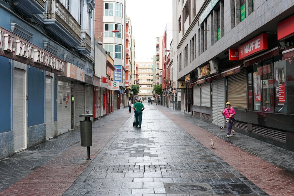 a couple of people walking down a street next to tall buildings