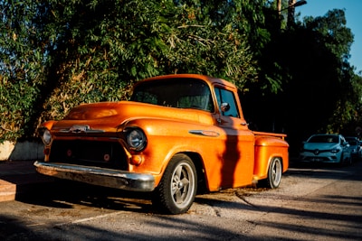 A restored 1950s pickup truck gleaming under the sun on a country road.