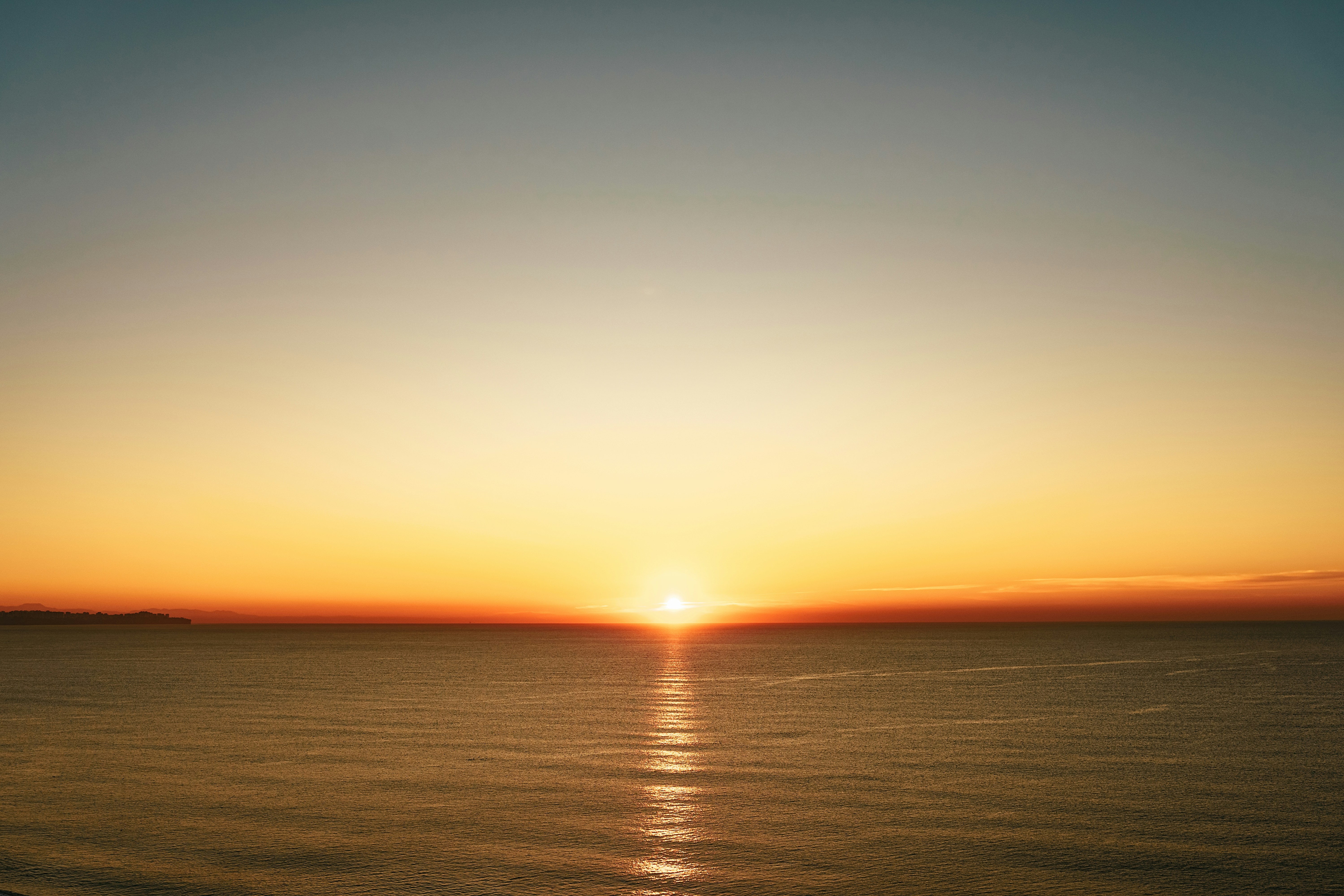 the sun is setting over the ocean on a clear day