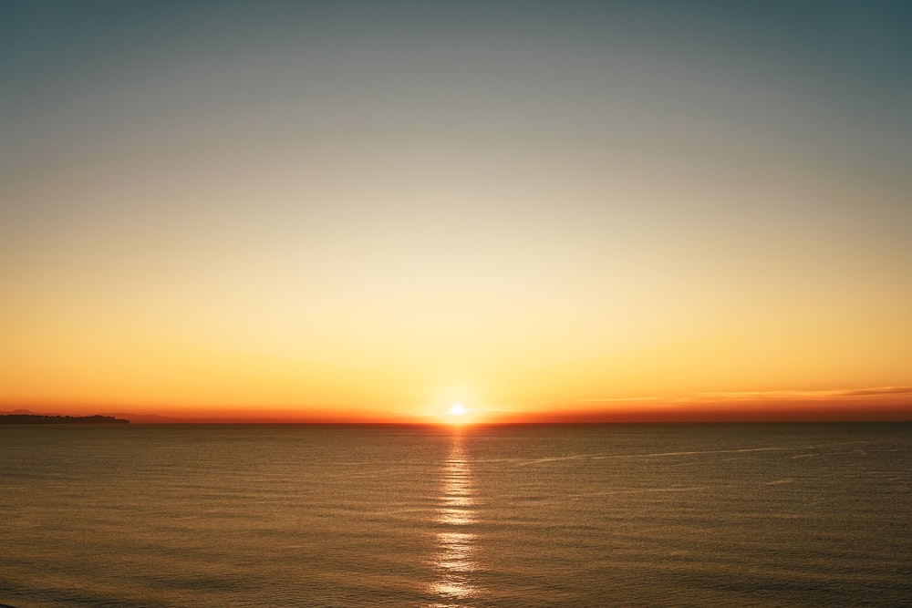 the sun is setting over the ocean on a clear day