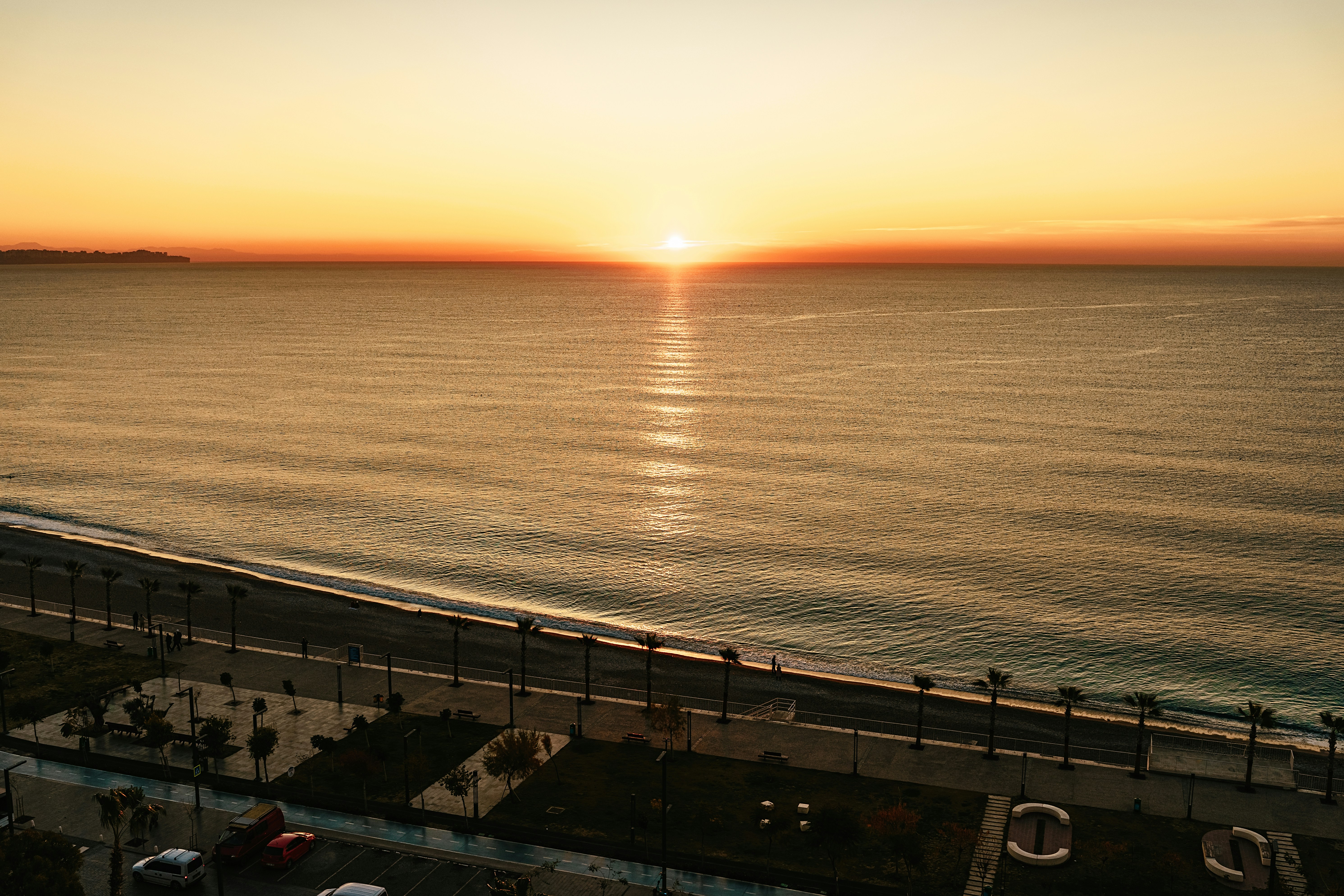 the sun is setting over the ocean on the beach