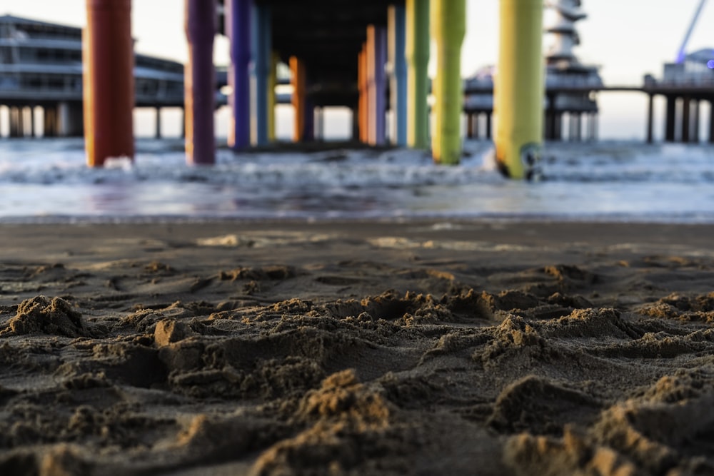 a sandy beach with a pier in the background