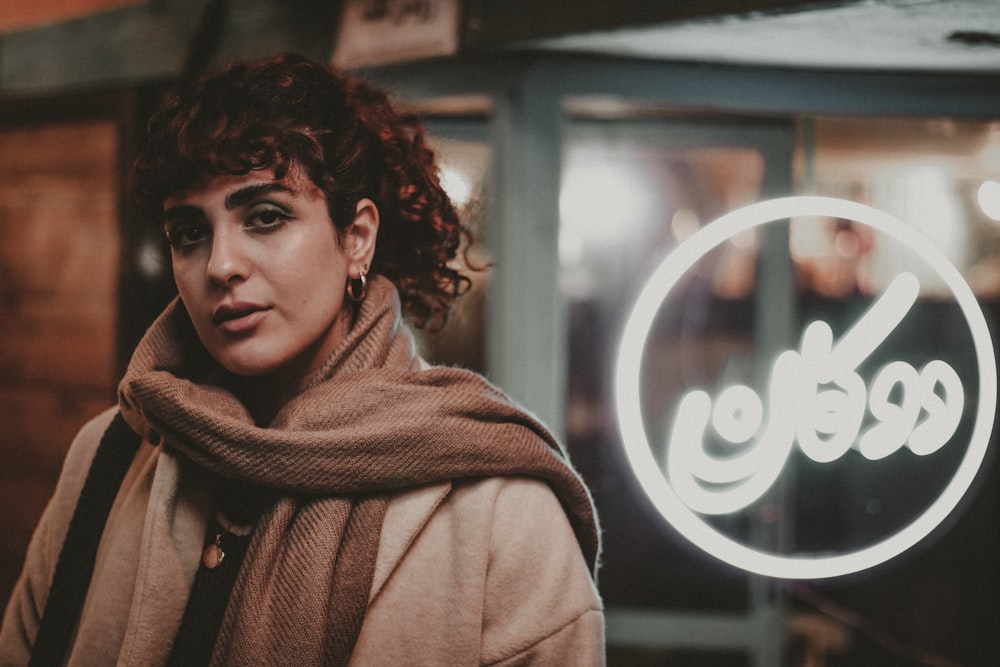 a woman standing in front of a neon sign