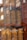Tall, cylindrical tea containers with the label 'PALOMA TEA COMPANY' are neatly arranged on wooden shelves. The containers have a matte finish, and reflections of lights and window panes can be seen on them, adding an artistic touch.