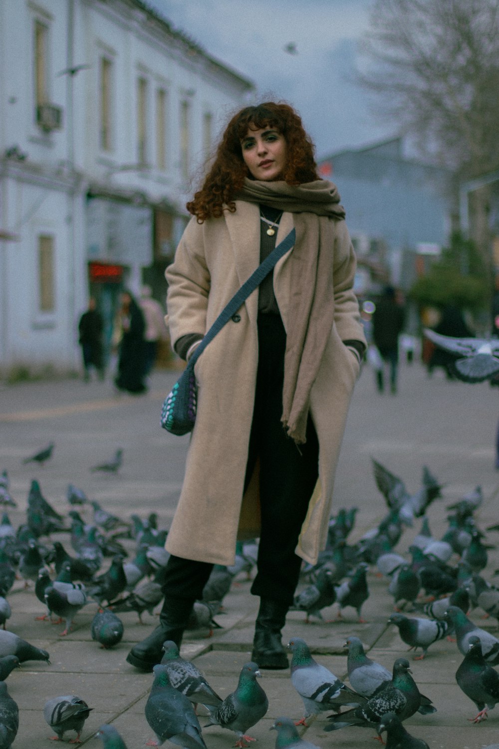 a woman standing in front of a flock of pigeons