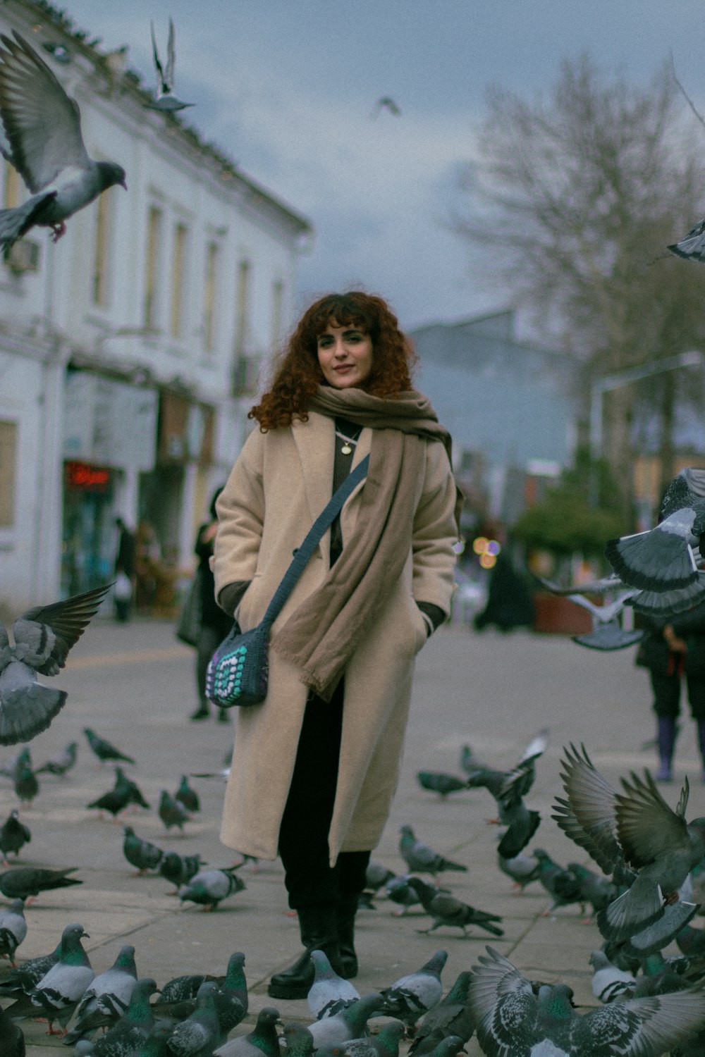 a woman standing in front of a flock of pigeons