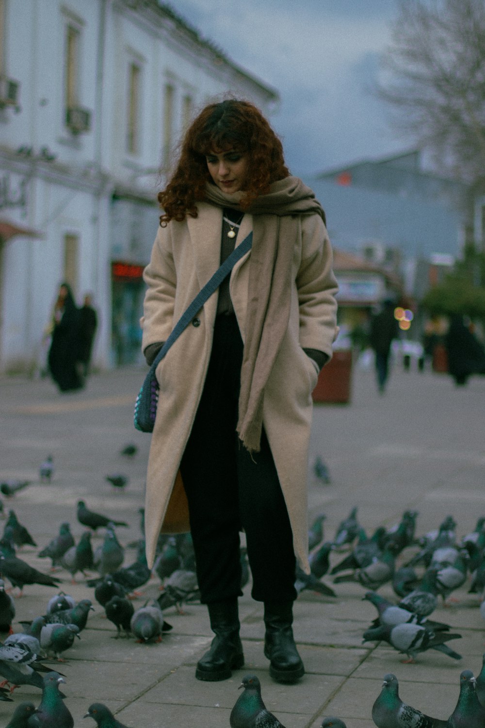 a woman standing in front of a flock of pigeons