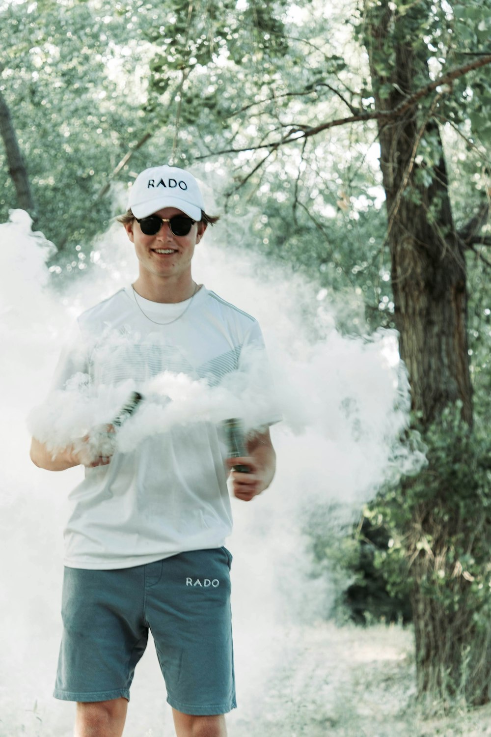 a man standing in a forest holding a smoke bomb