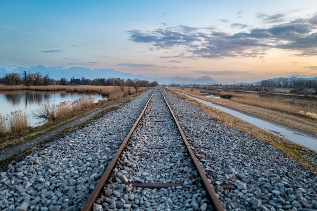 a train track with a body of water in the background,