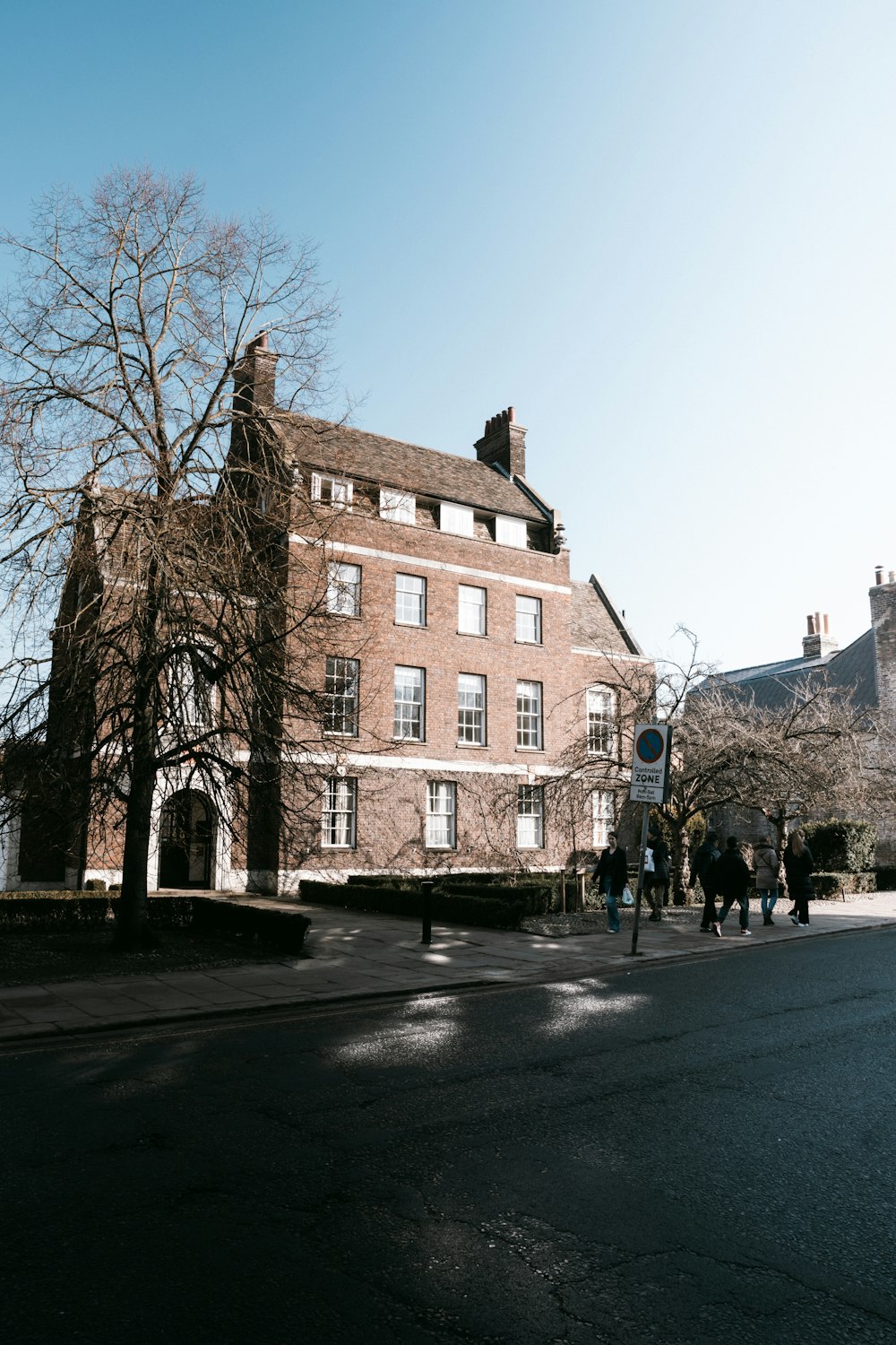 a group of people walking down a street next to a tall brick building