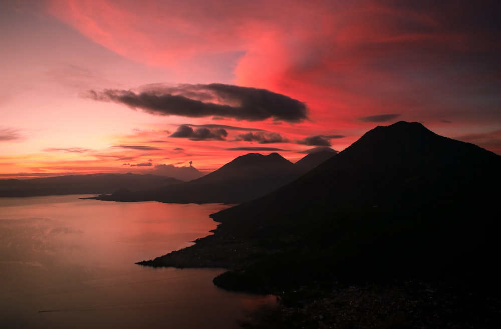 a sunset view of a mountain and a body of water